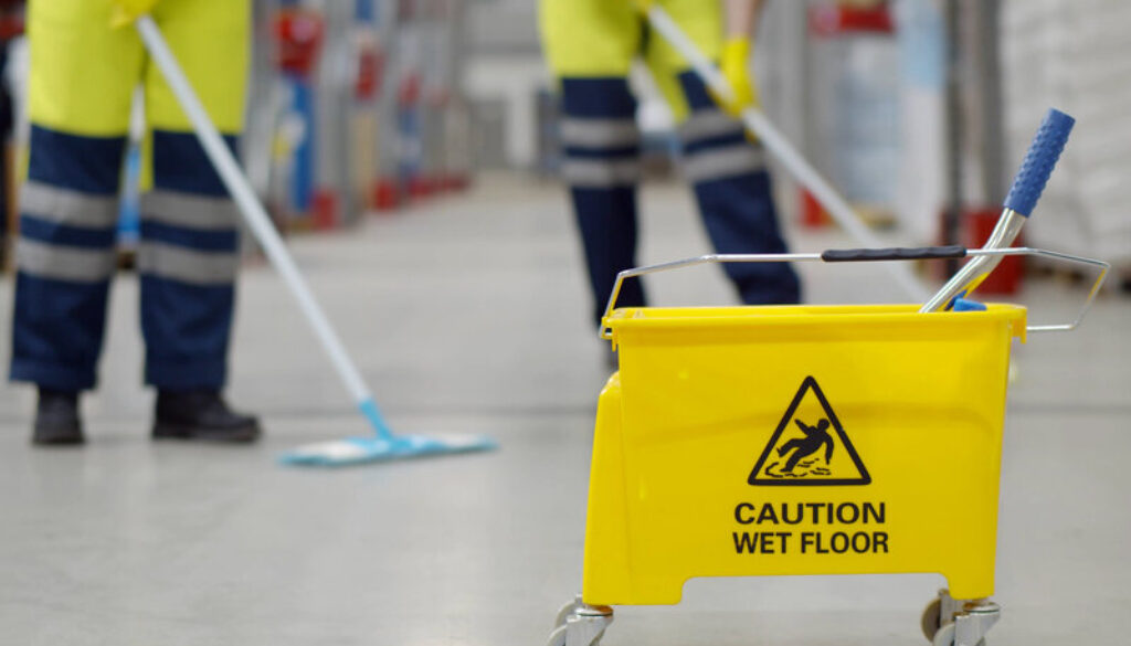 Cropped shot of worker swearing safety overall holding mop cleaning floor in warehouse