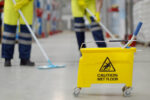 Cropped shot of worker swearing safety overall holding mop cleaning floor in warehouse