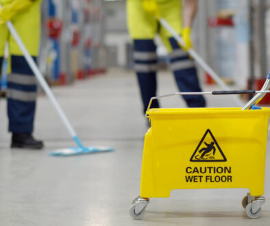 Cropped shot of worker swearing safety overall holding mop cleaning floor in warehouse